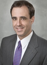 A man in a suit and tie smiling for the camera.