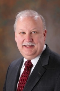 A man in a suit and tie smiling for the camera.