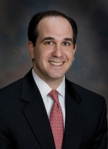 A man in suit and tie smiling for the camera.