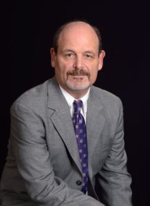 A man in a suit and tie sitting down.