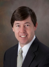 A man in suit and tie smiling for the camera.