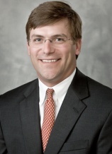 A man in a suit and tie smiling for the camera.