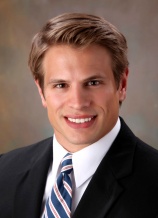 A man in suit and tie smiling for the camera.