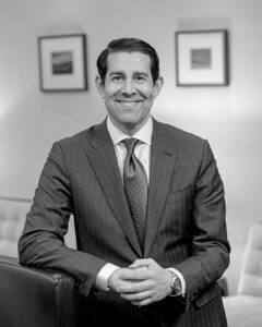A man in suit and tie sitting down.
