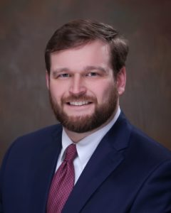 A man in a suit and tie smiling for the camera.