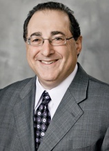A man in a suit and tie smiling for the camera.