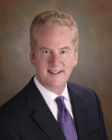 A man in suit and tie smiling for the camera.