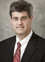 A man in suit and tie with glasses.