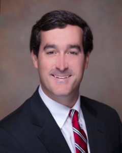 A man in suit and tie smiling for the camera.