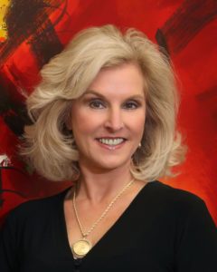 A woman with blonde hair wearing black is smiling.