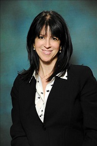 A woman in black jacket and white shirt smiling.