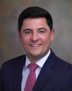 A man in a suit and tie smiling for the camera.